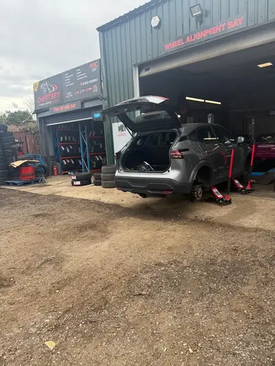 Chertsey Tyres & Service Centre workshop on Free Prae Road, Chertsey, with the wheel alignment bay open and a car being worked on