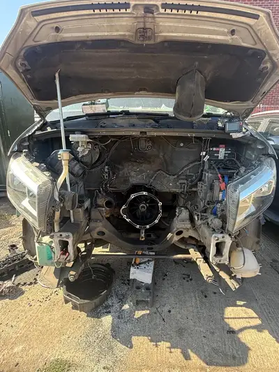 A van with its front end stripped down for repair outside the workshop