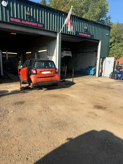 Front of the Chertsey Tyres & Service Centre workshop units with a small car on a jack outside the bays