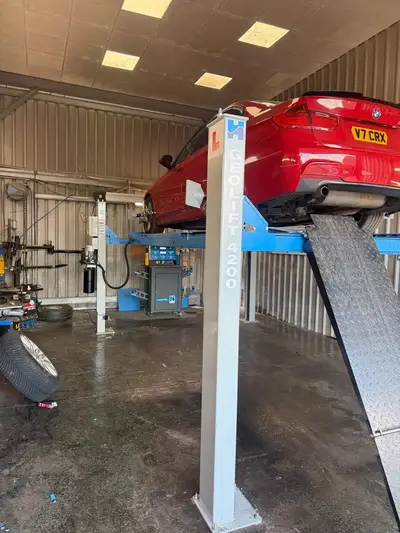 A car raised on the wheel alignment ramp inside the Chertsey workshop